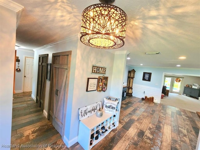 corridor with dark wood-type flooring, a textured ceiling, and ornamental molding