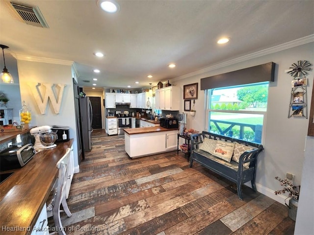 kitchen featuring wooden counters, white cabinets, sink, hanging light fixtures, and dark hardwood / wood-style floors