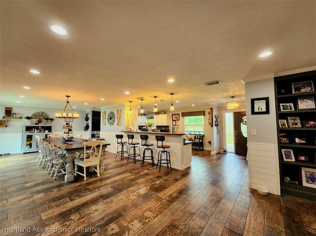 dining area featuring a notable chandelier, ornamental molding, and dark wood-type flooring