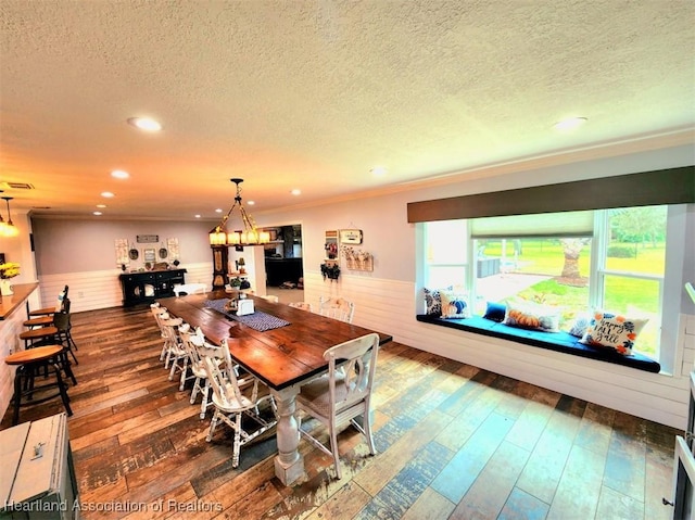 dining room featuring a chandelier, dark wood-type flooring, a textured ceiling, and ornamental molding