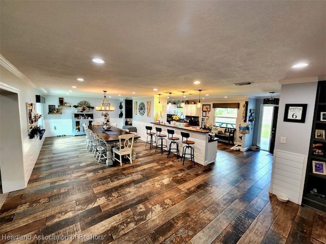 dining area with a textured ceiling, ornamental molding, and dark wood-type flooring