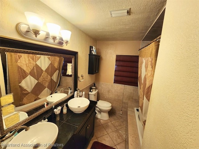 full bathroom with vanity, a textured ceiling, shower / tub combo with curtain, tile patterned flooring, and toilet