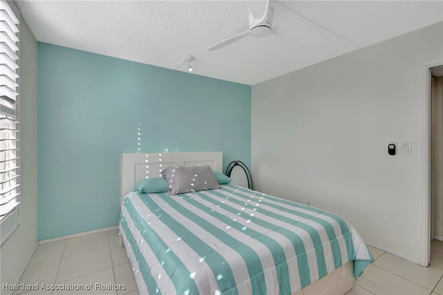 tiled bedroom with a textured ceiling and ceiling fan