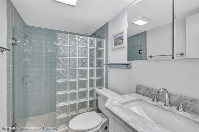 bathroom with toilet, an enclosed shower, and vanity