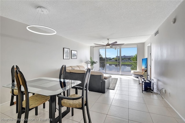 dining space featuring ceiling fan, expansive windows, light tile patterned floors, and a textured ceiling