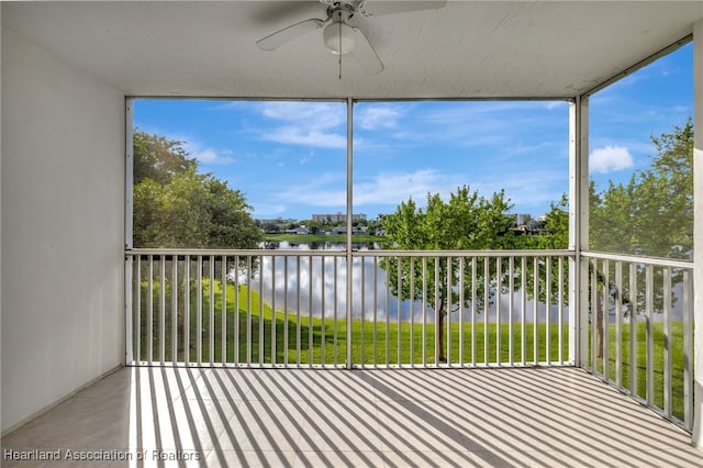 unfurnished sunroom featuring ceiling fan and a water view