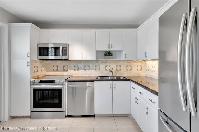 kitchen with backsplash, sink, light tile patterned floors, stainless steel appliances, and white cabinets