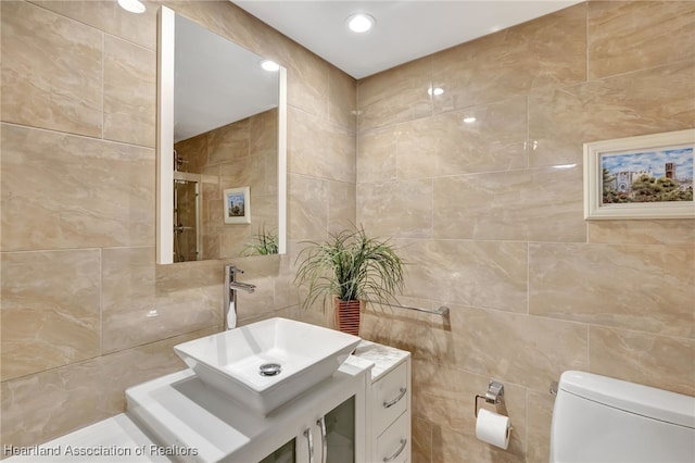 bathroom with tile walls, toilet, vanity, and walk in shower