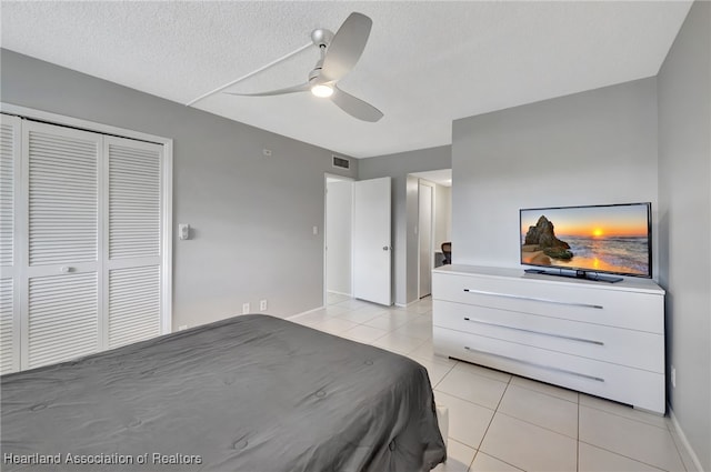 tiled bedroom with ceiling fan, a textured ceiling, and a closet