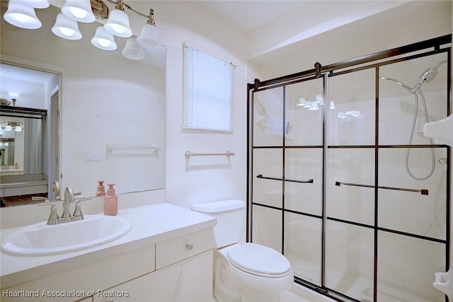 bathroom featuring vanity, toilet, and a shower with door