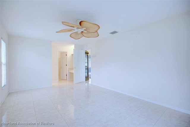 tiled spare room featuring ceiling fan and a healthy amount of sunlight