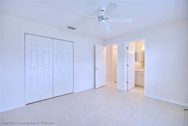 unfurnished bedroom with ceiling fan, a closet, light tile patterned floors, and ensuite bath