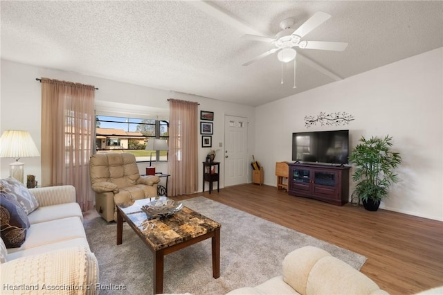 living room featuring ceiling fan, light hardwood / wood-style floors, and a textured ceiling