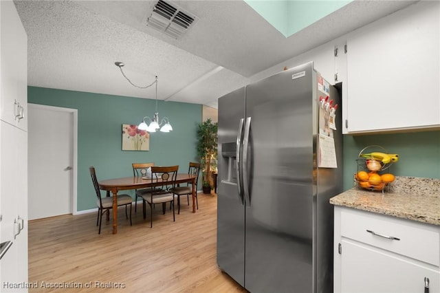 kitchen with white cabinetry, a textured ceiling, stainless steel fridge, pendant lighting, and light hardwood / wood-style floors