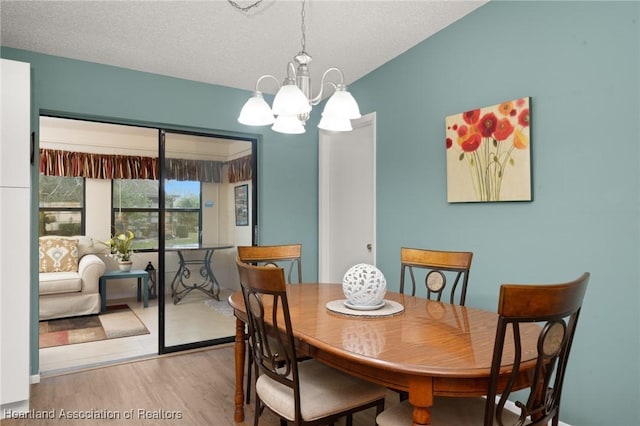 dining room featuring wood-type flooring, a notable chandelier, and a textured ceiling