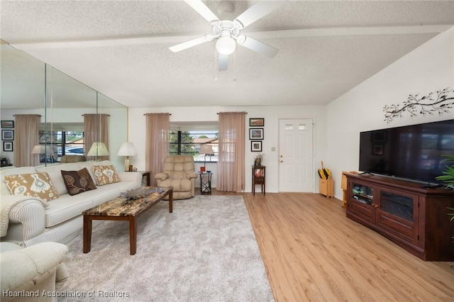 living room with ceiling fan, vaulted ceiling, light hardwood / wood-style flooring, and a textured ceiling