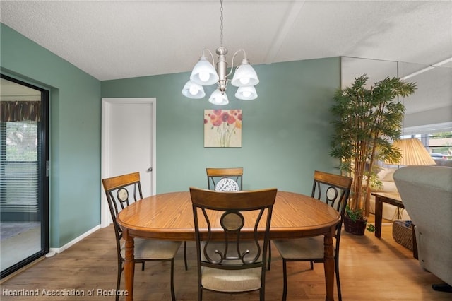 dining space featuring vaulted ceiling, hardwood / wood-style floors, a textured ceiling, and a notable chandelier