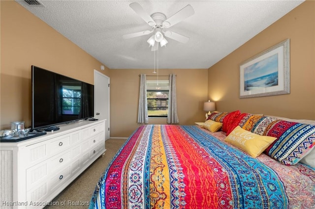 carpeted bedroom with ceiling fan and a textured ceiling