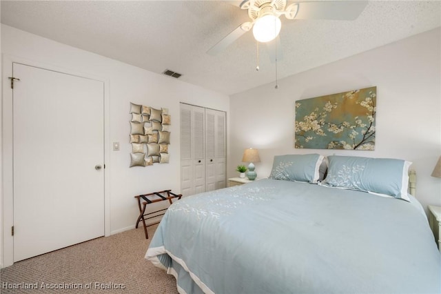 carpeted bedroom with ceiling fan, a closet, and a textured ceiling