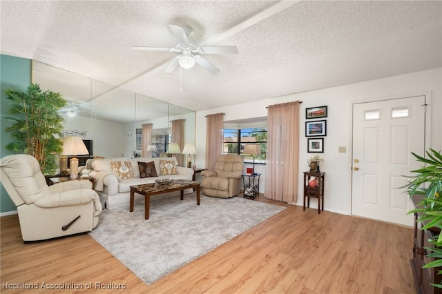 living room featuring hardwood / wood-style flooring, ceiling fan, and a textured ceiling