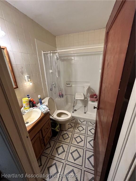 full bathroom featuring shower / bath combo, vanity, toilet, and tile walls