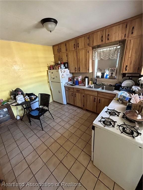 kitchen featuring sink, light tile patterned flooring, and white appliances