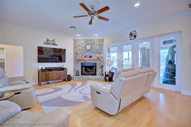 living area with ornamental molding, light wood-type flooring, a fireplace, and visible vents