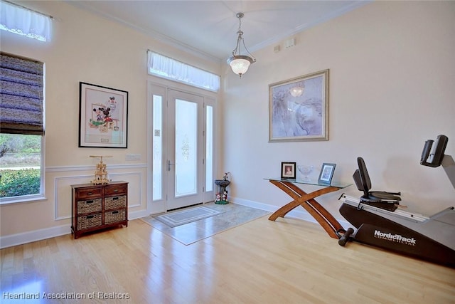 foyer featuring crown molding, baseboards, and wood finished floors