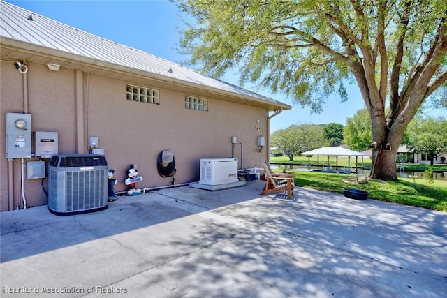 view of side of property featuring metal roof, stucco siding, a patio, and central air condition unit