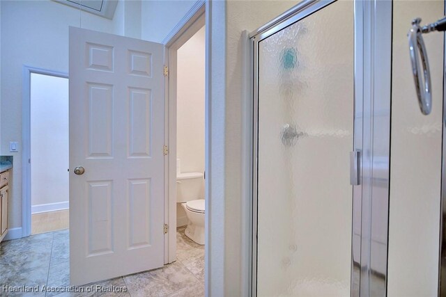 bathroom featuring baseboards, toilet, vanity, and a shower stall