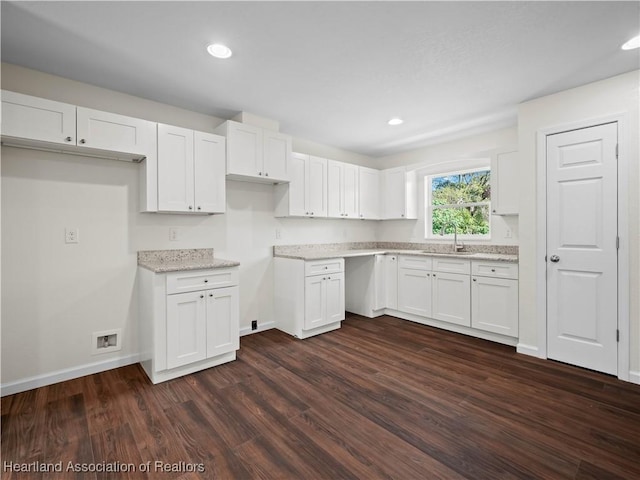 kitchen with white cabinets, dark hardwood / wood-style flooring, light stone countertops, and sink