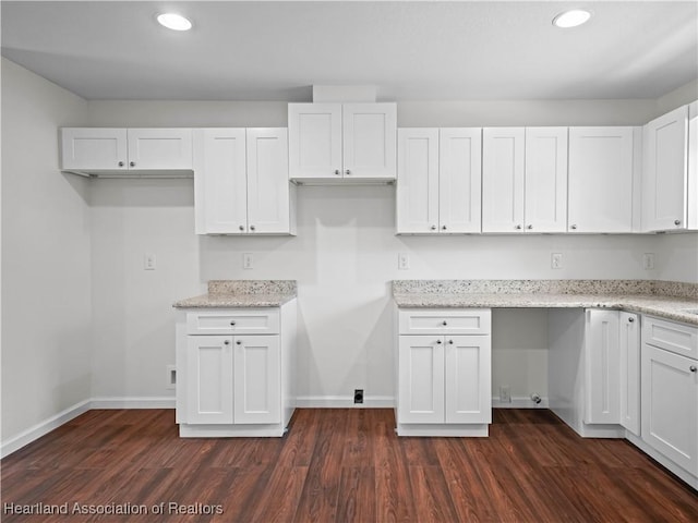 kitchen featuring white cabinets, light stone counters, and dark wood-type flooring