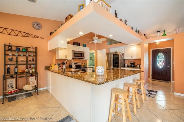 kitchen featuring sink, white cabinetry, dark stone countertops, kitchen peninsula, and stainless steel appliances