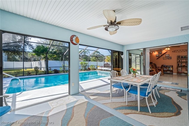 view of swimming pool with ceiling fan, a patio, and glass enclosure