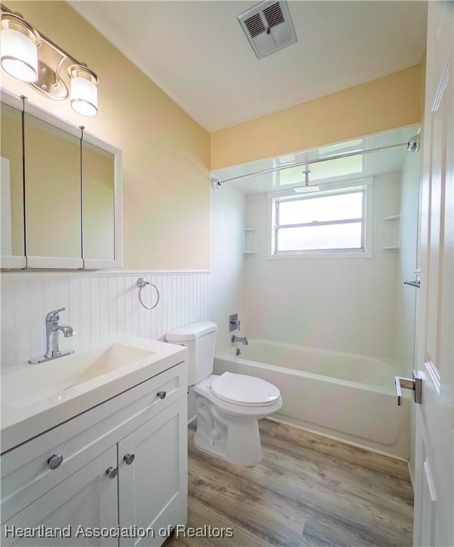 956 Shamrock Dr, Sebring, FL 33875 - full bathroom with wainscoting, wood finished floors, shower / bathtub combination, vanity, and toilet