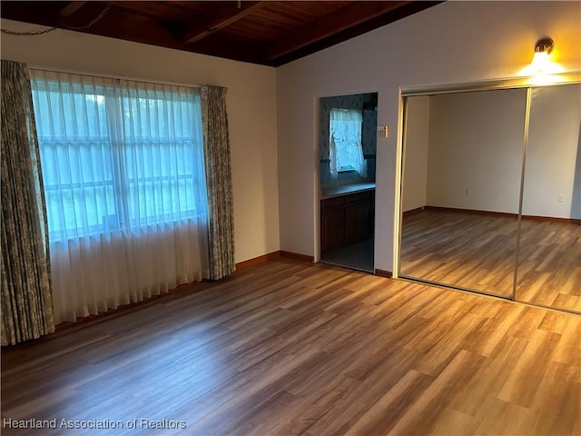 unfurnished bedroom featuring hardwood / wood-style floors, lofted ceiling with beams, a closet, and wood ceiling