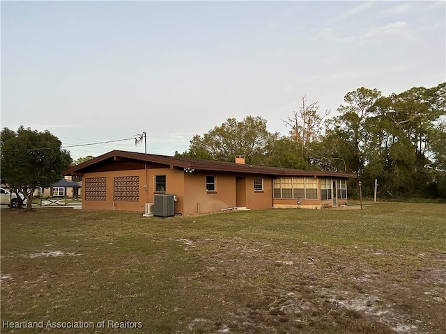 back of property with a sunroom, cooling unit, and a yard