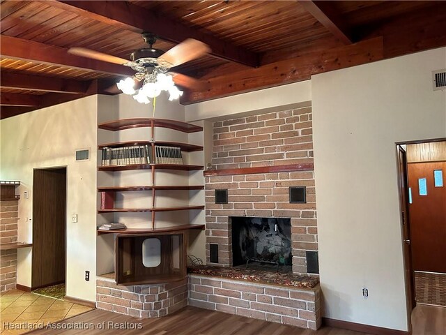 unfurnished living room featuring beamed ceiling, ceiling fan, light wood-type flooring, and a fireplace