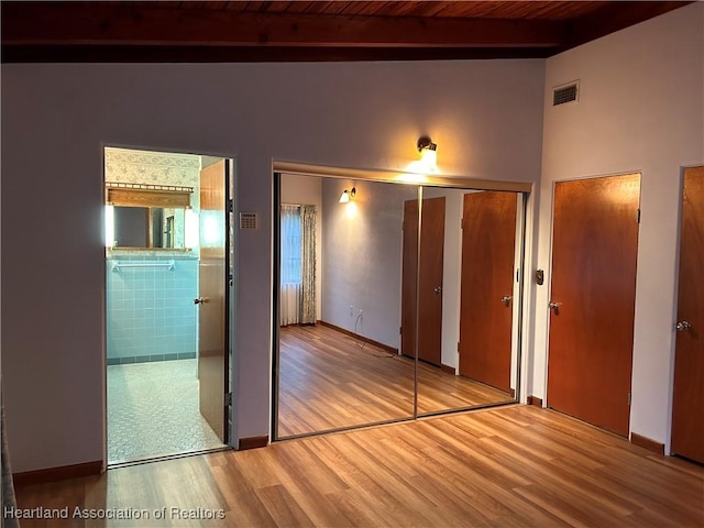 unfurnished bedroom featuring beamed ceiling, hardwood / wood-style flooring, and wood ceiling