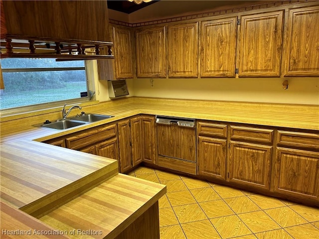 kitchen with paneled dishwasher, light tile patterned floors, wooden counters, and sink