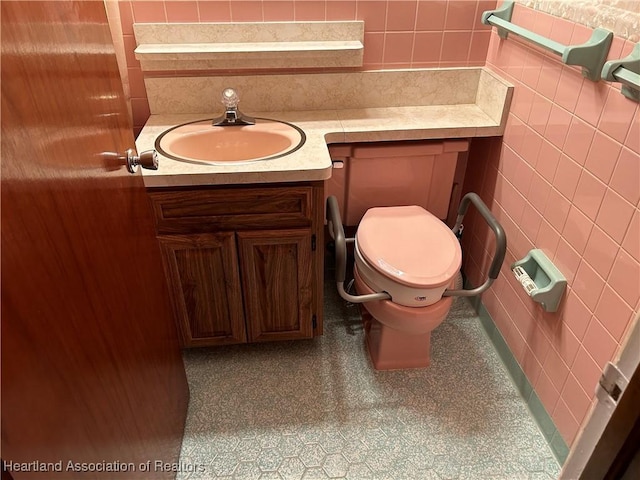 bathroom with vanity, toilet, and tile walls