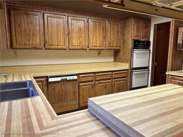 kitchen with dishwasher, white double oven, wooden counters, and sink