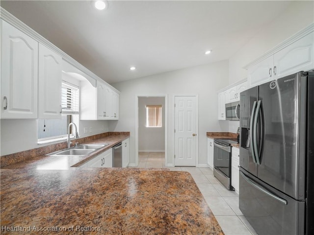 kitchen with light tile patterned flooring, vaulted ceiling, sink, white cabinets, and stainless steel appliances