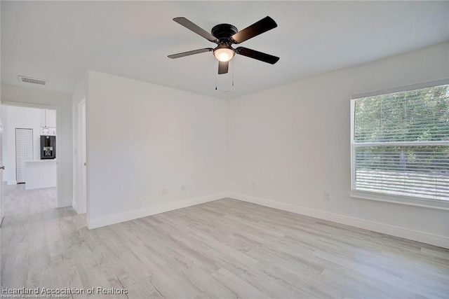 spare room featuring baseboards, visible vents, light wood finished floors, and ceiling fan