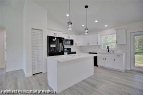 kitchen with light wood-type flooring, white cabinets, light countertops, and fridge