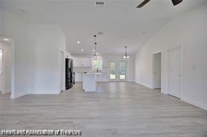 unfurnished living room featuring a ceiling fan, light wood-style floors, and high vaulted ceiling