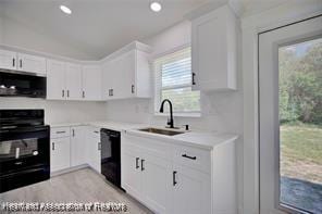 kitchen featuring a sink, white cabinetry, black appliances, and light countertops