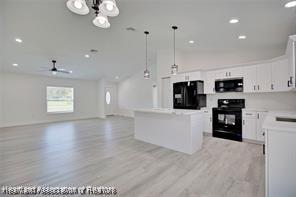 kitchen with black appliances, white cabinets, light wood-style floors, and a center island