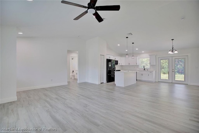 unfurnished living room featuring a sink, baseboards, lofted ceiling, and light wood-style floors