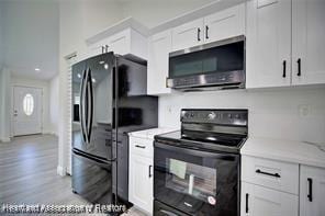 kitchen featuring white cabinetry, black appliances, light wood-style floors, and light stone countertops